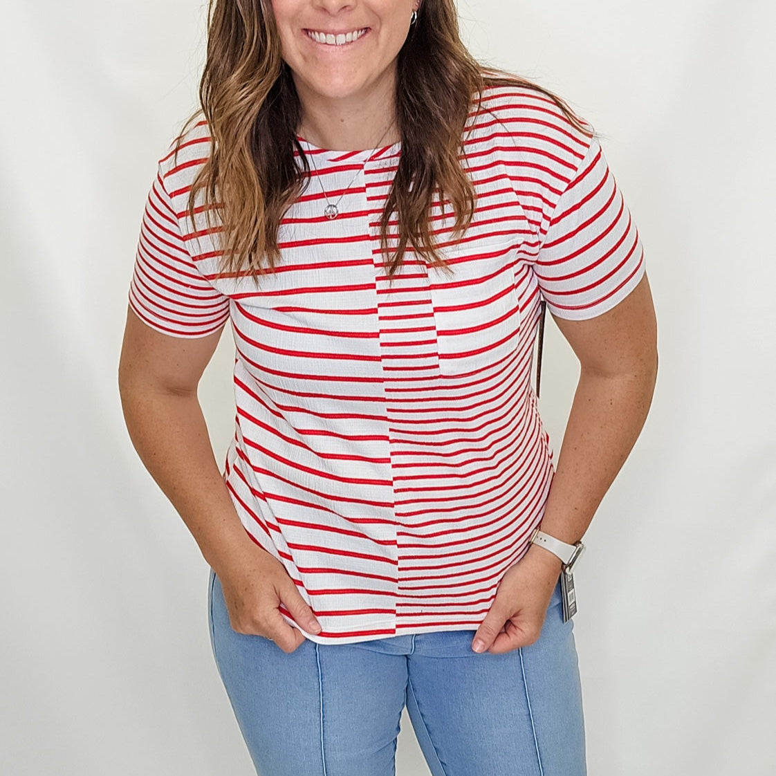 Woman wearing a red and white striped shirt and blue jeans on a white background