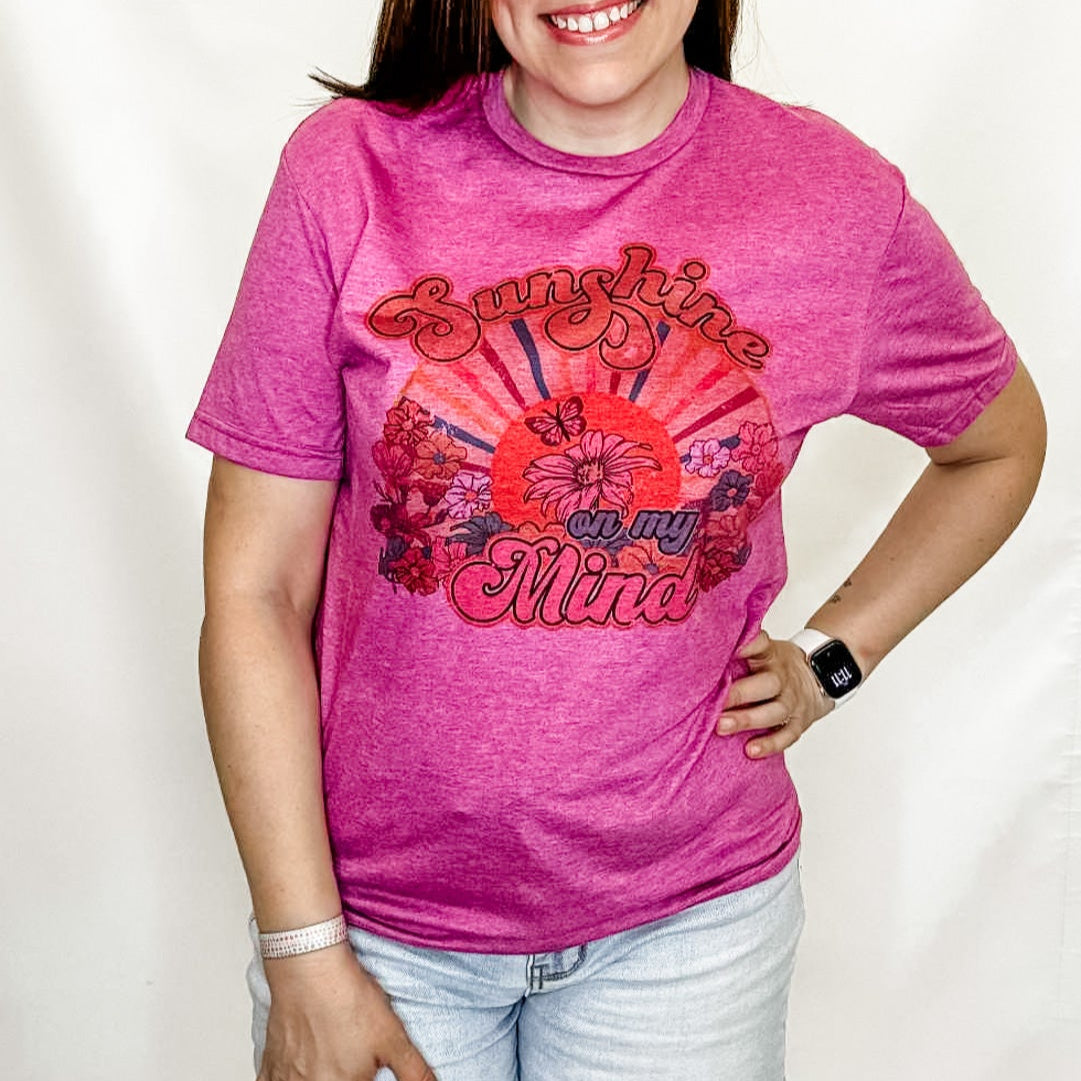 Person wearing a pink t-shirt with red graphics and text on a white background
