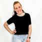 Woman wearing a black top and denim shorts on a white background