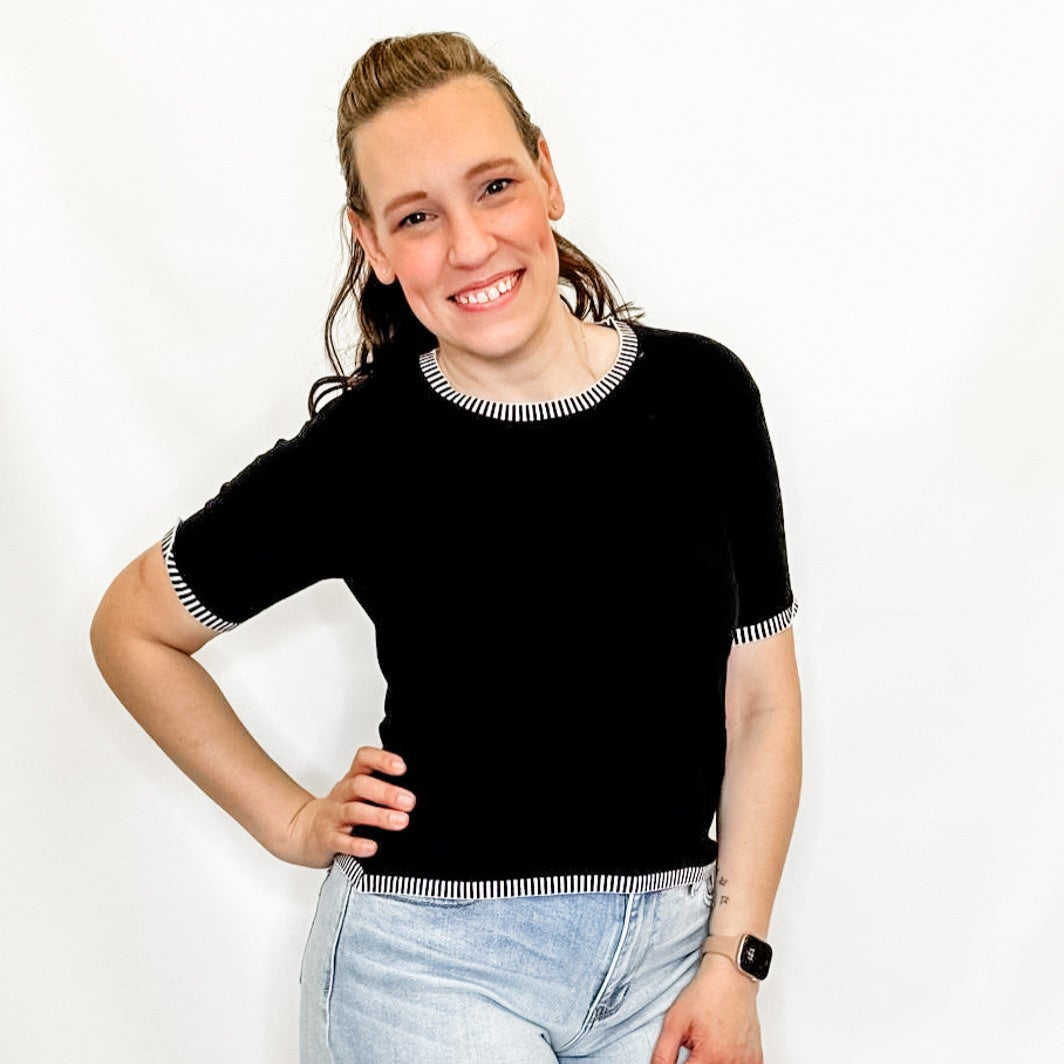Woman wearing a black top and denim shorts on a white background