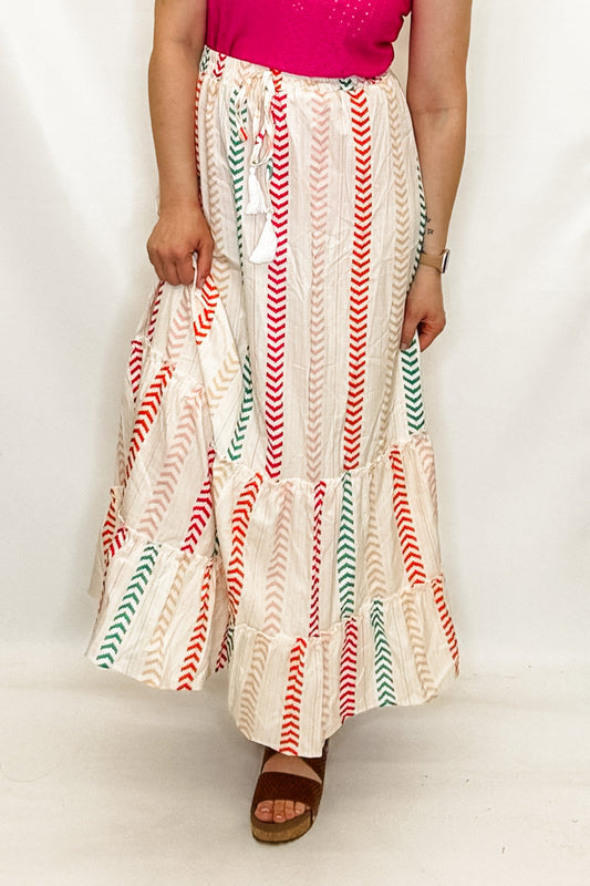 Woman wearing a pink top and colorful skirt on a white background